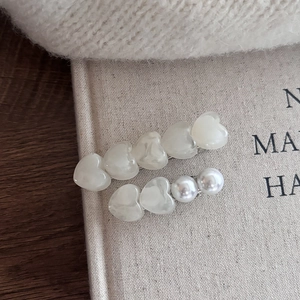 Detalle de horquillas para el pelo con perlas de corazón y textura de resina jaspeada
