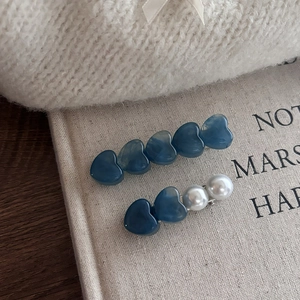 Detalle de pinzas para el cabello de corazones azules y perlas sobre fondo suave