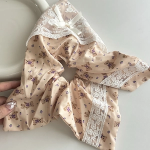 Dettaglio scrunchie floreale rosa con stampa orso, bordo in pizzo bianco e fiocco