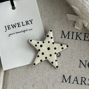 Star-shaped hair clip with black polka dots on cream enamel and silver metal edges