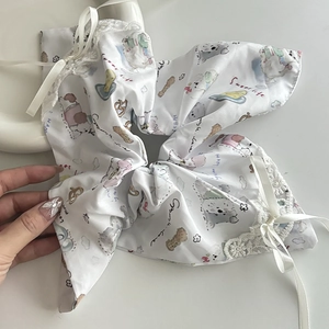 Dettaglio di scrunchie in raso bianco con stampe di cuccioli e bordi in pizzo