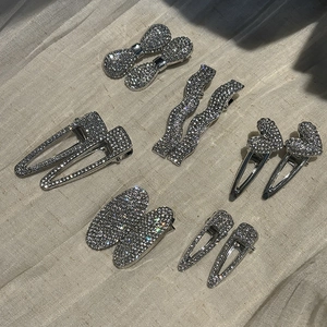 Sparkling rhinestone bow and geometric metal hair clips set on a soft beige fabric