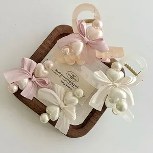 Elegante Haarklammern mit Herzperlen und Schleifen in Rosa und Creme auf Tablett
