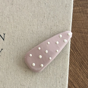 Dettaglio di un fermaglio per capelli viola a pois su sfondo in lino testurizzato