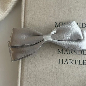 Detail einer silbernen Satin-Schleifen-Haarklammer mit metallischer Textur im Vintage-Stil