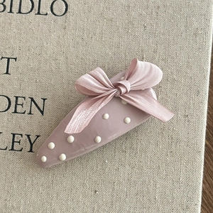 Dettaglio del fermaglio a goccia rosa a pois con un fiocco in nastro di raso