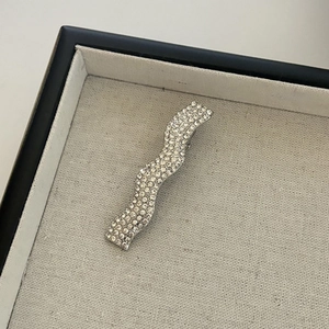 Close-up detail of silver wavy hair clip with sparkling rhinestones on jewelry tray