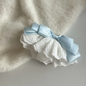 Pince à cheveux nœud bleu clair avec dentelle brodée blanche sur fond en peluche