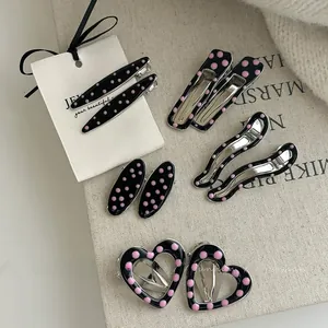 Détail de cinq barrettes géométriques en métal à pois noirs et roses pour filles