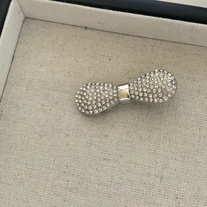 Detailed macro view of silver bow hair clip with sparkling rhinestones on beige fabric