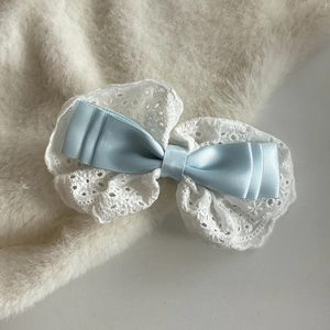 Détail d'une barrette à nœud en satin bleu clair avec broderie en dentelle blanche