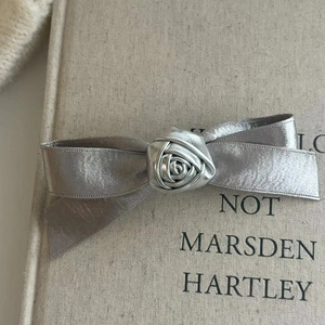 Makroaufnahme der silbernen Satin-Schleife-Haarklammer mit handgefertigter Rose