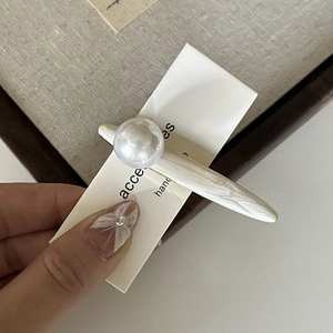 Vue détaillée d'une barrette en perle élégante sur une carte crème de style minimaliste