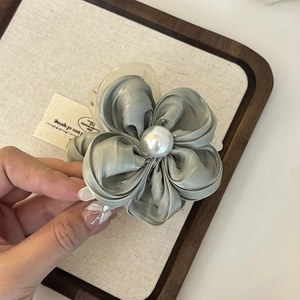 Detail einer seidigen grauen Blumen-Haarklammer mit einer Perle und cremefarbener Basis