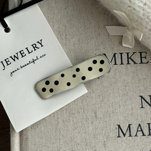 Close-up of retro black polka dot hair clip on jewelry card with rustic fabric background