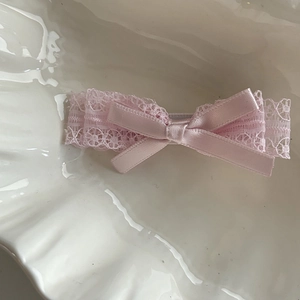 Détail de la pince à cheveux en dentelle rose avec ruban plissé et centre satin