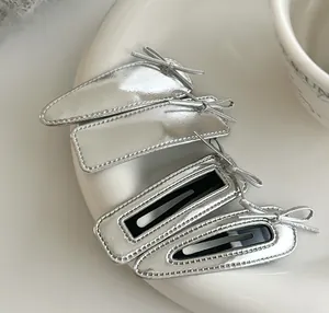 Close-up of metallic silver leather hair clips set with ribbon bows on ceramic plate