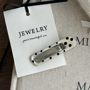 Detailed view of polka dot pattern BB hair clip on a premium jewelry display card