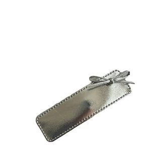 Silver metallic leather bow hair clip with textured rectangle base on white background