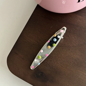 Détail de la pince à cheveux en métal argenté avec des pois colorés peints à la main