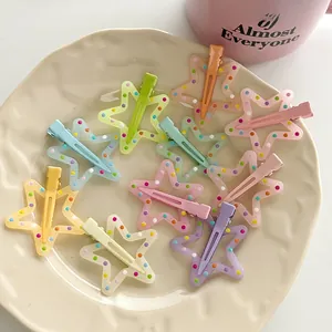 Macro shot of colorful star hair clips with polka dots arranged on a cream ceramic plate