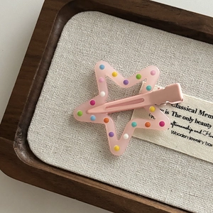 Pink star hair clip with colorful polka dots on a wooden tray for girls and kids