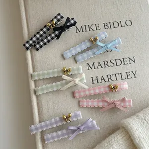 Five pairs of plaid bow hair clips in pastel colors on vintage book page background