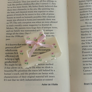 Floral square hair claw clip in cream with pink ribbon bow on a vintage book