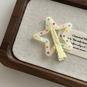 Cute star-shaped hair clip with colorful polka dots on a cream resin finish