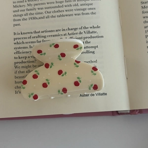 Detail of cream hair claw clip with red floral and white polka dot patterns on a book