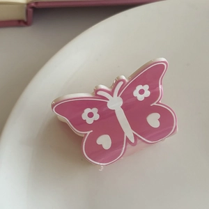 Detail of pink butterfly hair claw clip with floral patterns on white ceramic plate