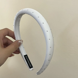 Close-up of white padded headband with silver studs and handmade label detail