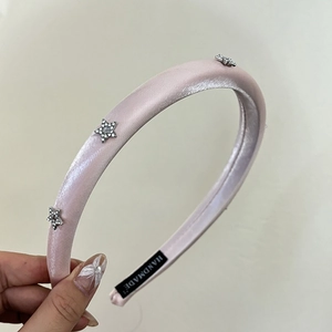 Detailed view of pink padded headband with rhinestone stars and handmade label