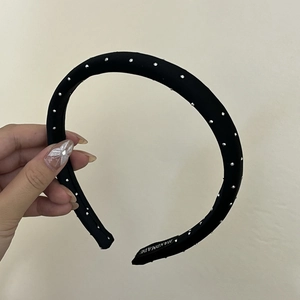Close-up of handmade black satin headband with silver stud accents and interior label