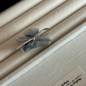 Elegant silver bow hair claw clip with marble texture displayed in a velvet box
