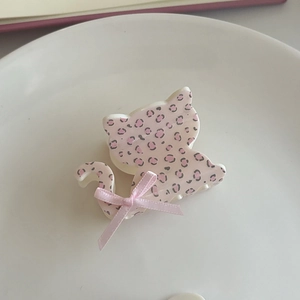 Close-up of pink leopard print cat hair claw clip with silk bow on white plate