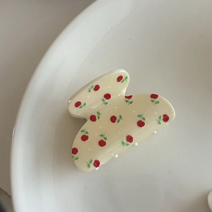 Close-up of floral hair claw clip with red roses on cream yellow acetate base