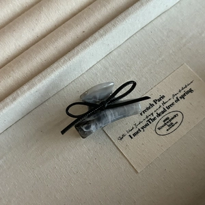 Detail of small marble claw clip with black ribbon bow on premium fabric background