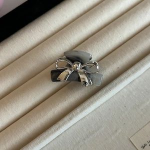 Detail of grey marble claw clip featuring a silver metal bow on a soft fabric stand
