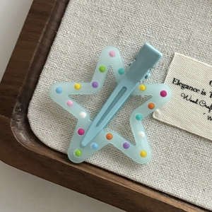 Detail shot of light blue star-shaped resin hair clip with multi-colored polka dots