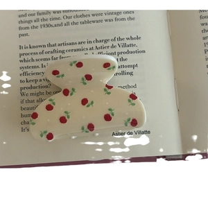 Elegant floral claw clip with red roses on cream base displayed on a vintage book