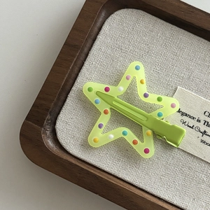 Close-up of star-shaped hair clip in light green with colorful polka dots and metal base