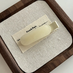 Dettaglio molletta per capelli opaca crema su carta con base in metallo argento