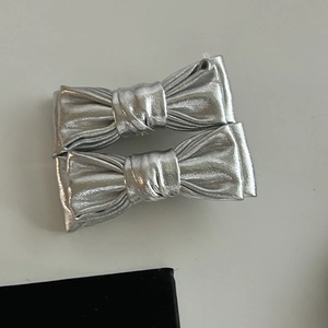 Close-up of metallic silver bow hair clips with textured finish and accordion pleats