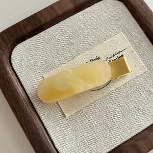 Dettaglio del fermaglio per capelli effetto marmo giallo con base in metallo dorato