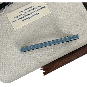 Barrette à cheveux en denim bleu avec texture vintage sur un fond gris minimaliste