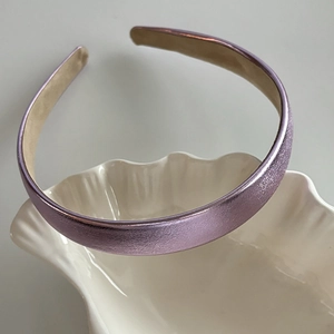 Détail d'un serre-tête métallique violet clair sur plat en coquillage blanc avec ombre