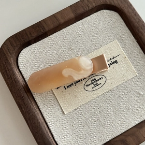 Dettaglio del fermaglio per capelli in resina beige marmorizzata con base in oro rosa