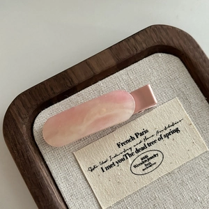 Dettaglio di un fermaglio per capelli in acetato rosa marmorizzato con glitter fini