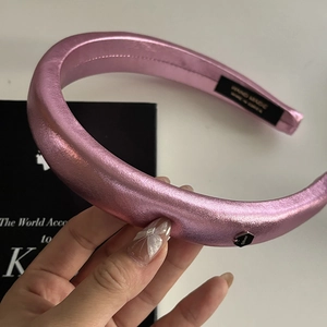 Detail view of pink satin padded headband showing hand made label and silver hex accent